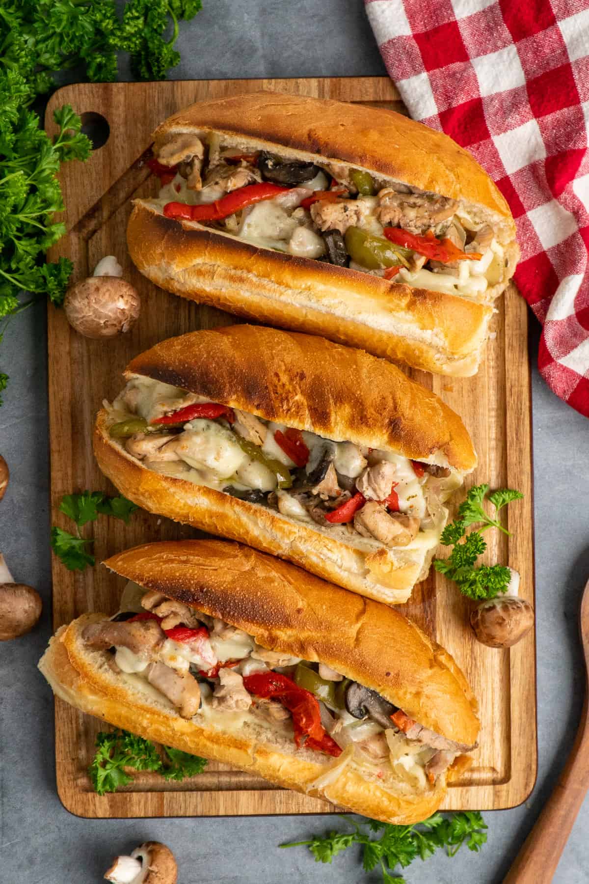 Chicken Philly cheesesteaks on a wooden cutting board.