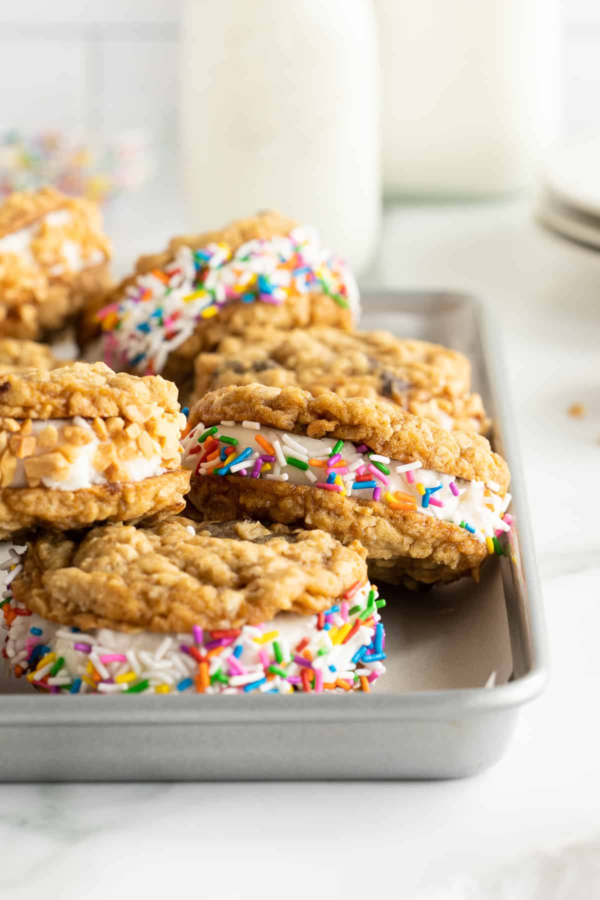 Oatmeal cookie ice cream sandwiches with sprinkles in a cookie sheet.