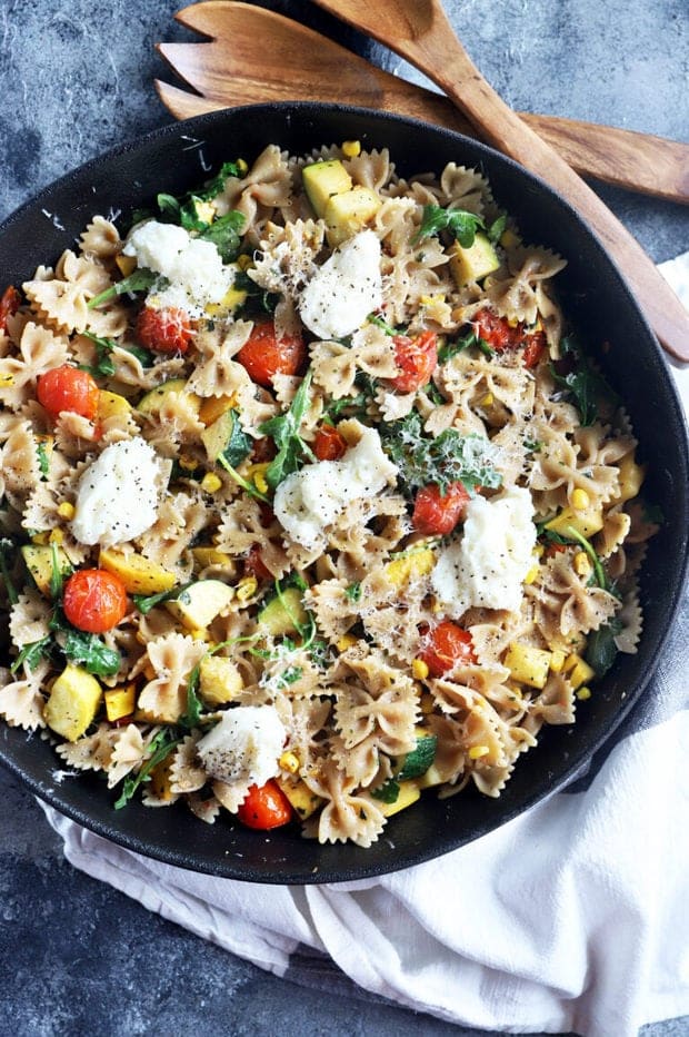 Colorful pasta recipe with summer squash and corn in a black bowl.