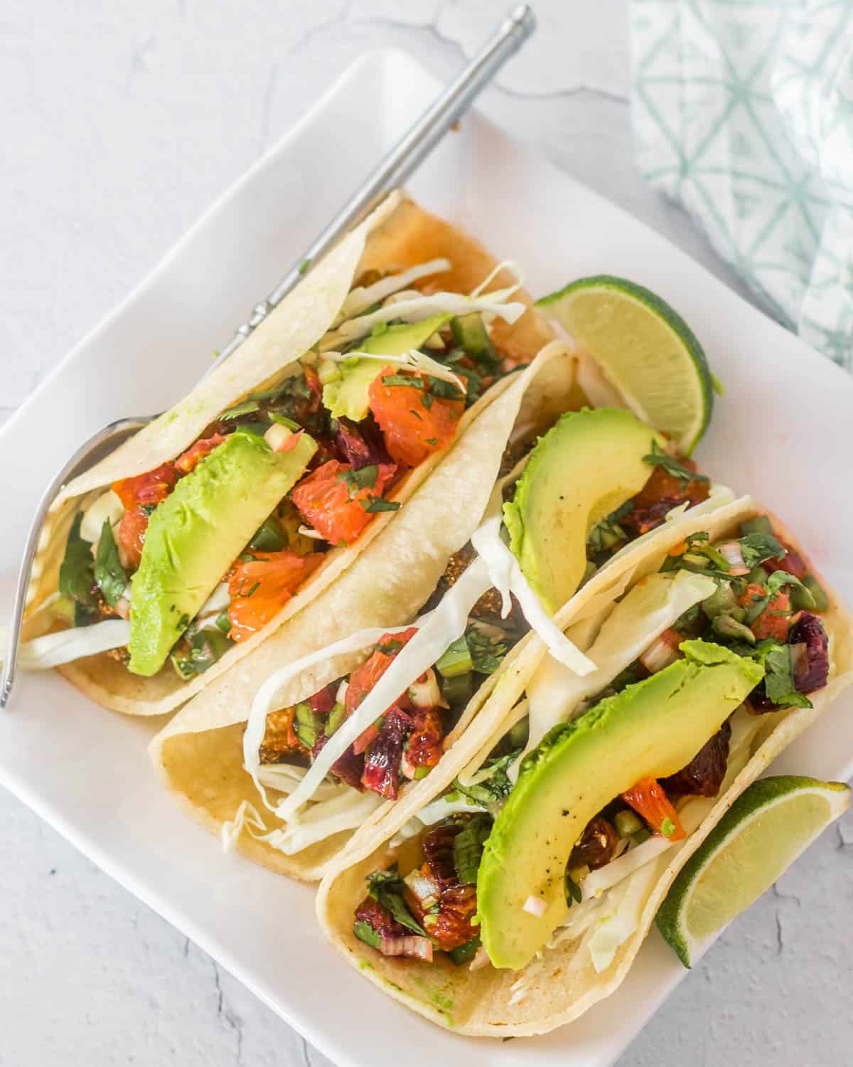 Fried oyster tacos with citrus salsa on a white square plate.