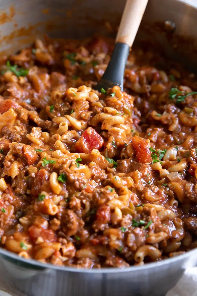 American goulash in pan with a spoon.