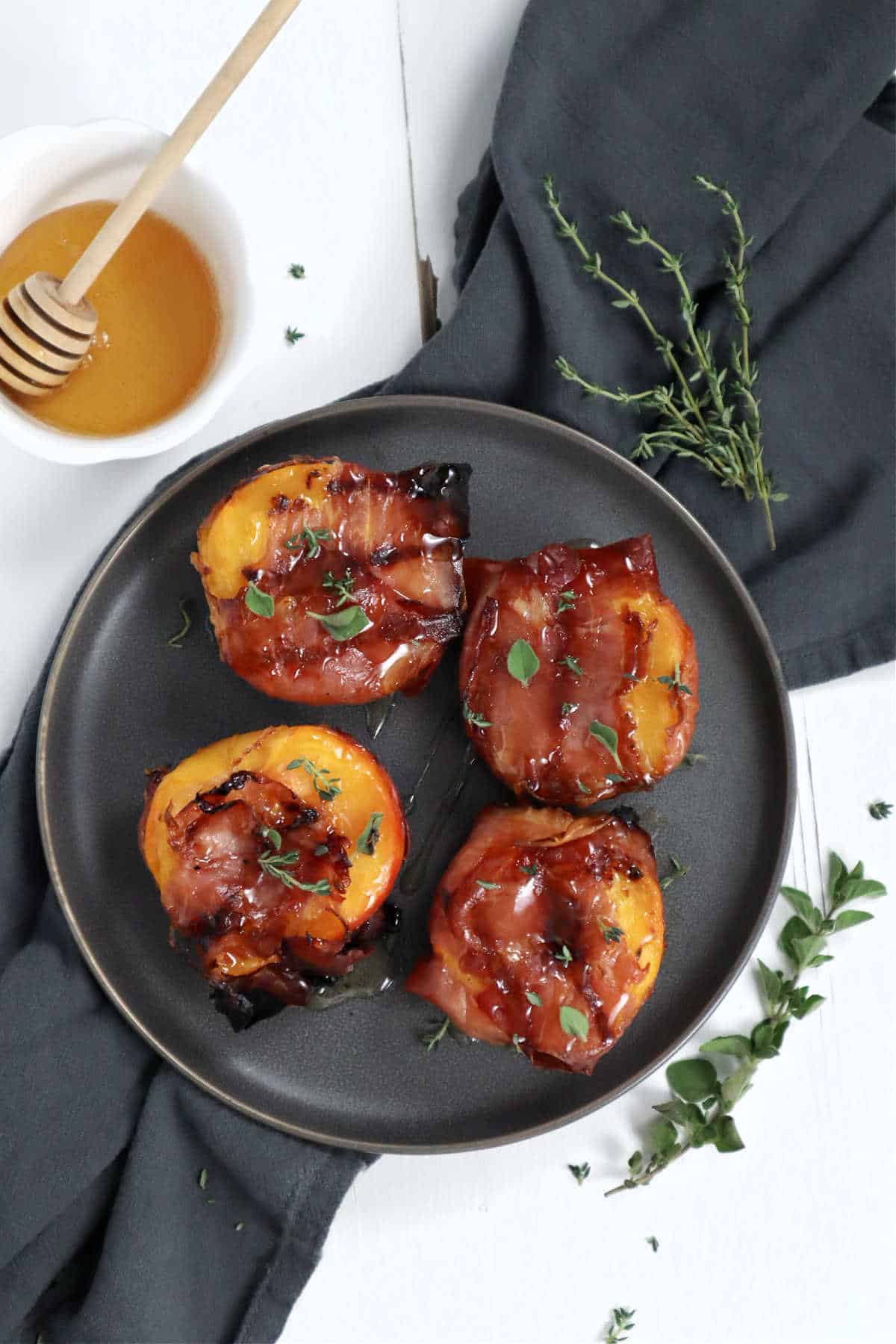 Bacon wrapped peaches on a grey plate.