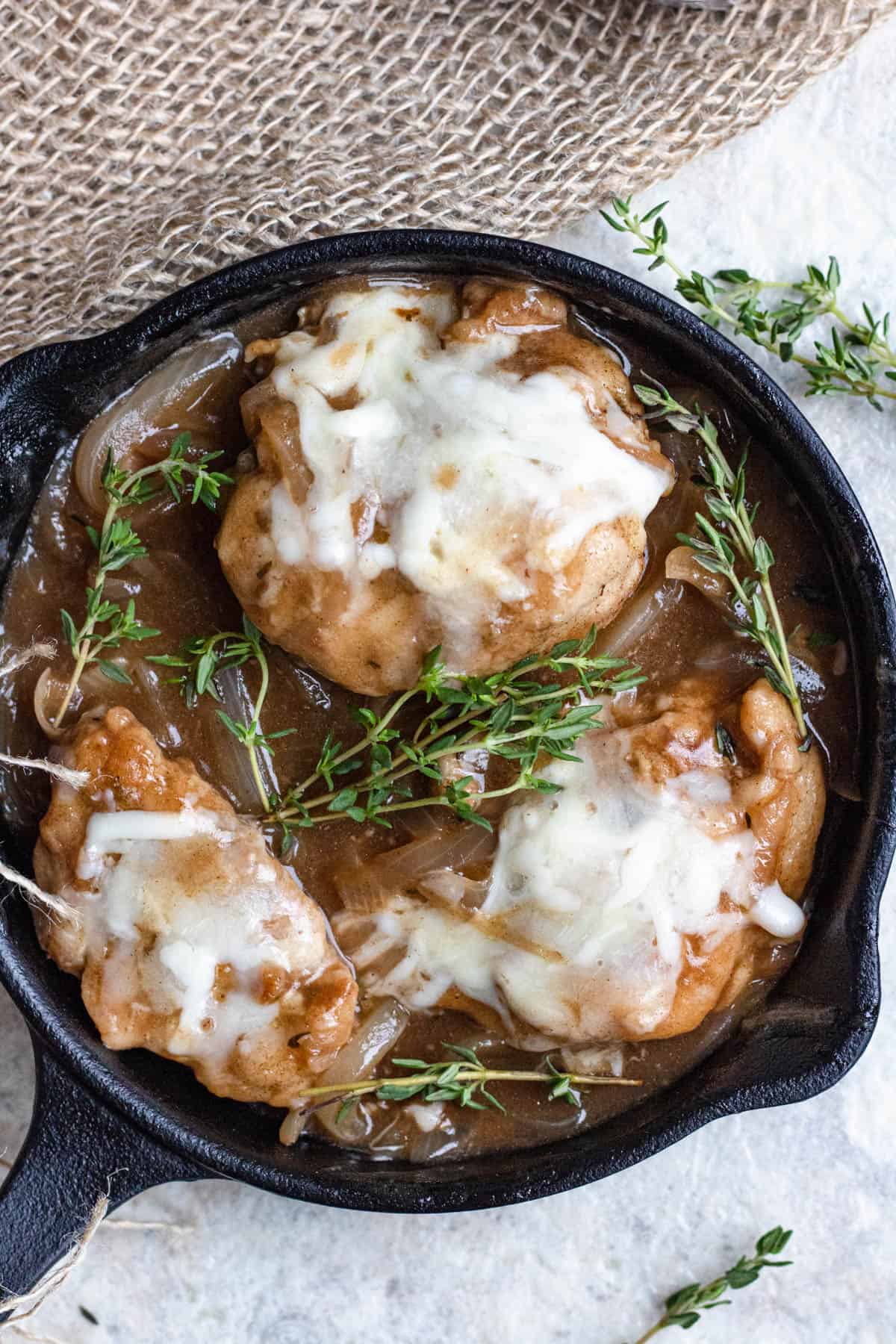 French onion chicken in a cast iron pan with herbs.