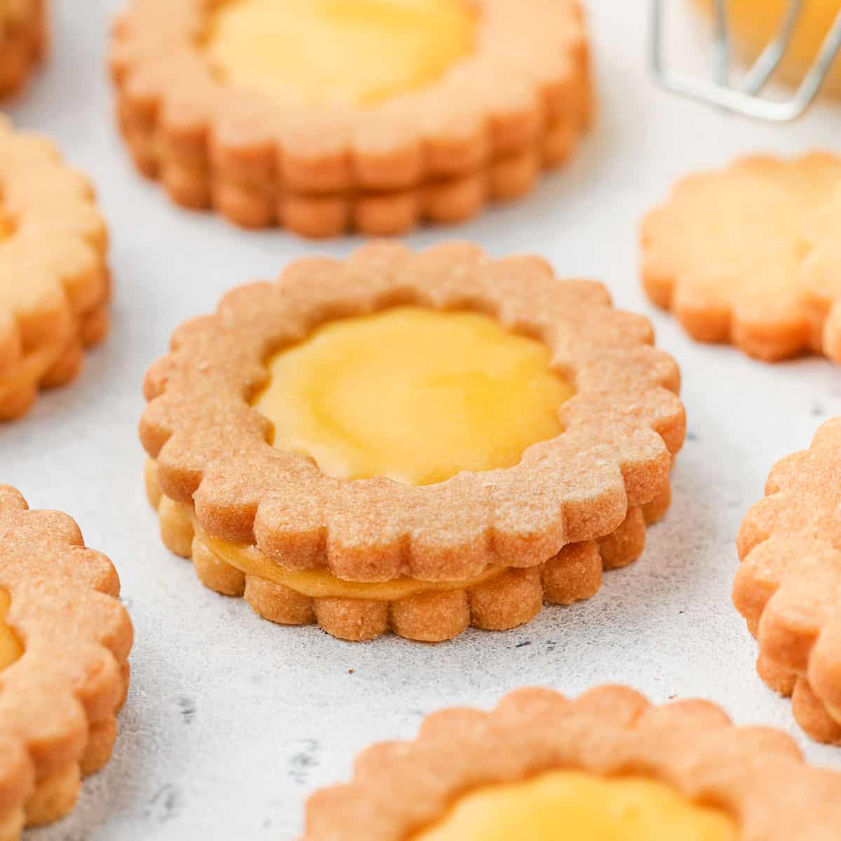 Closeup of lemon curd cookies on a white surface.