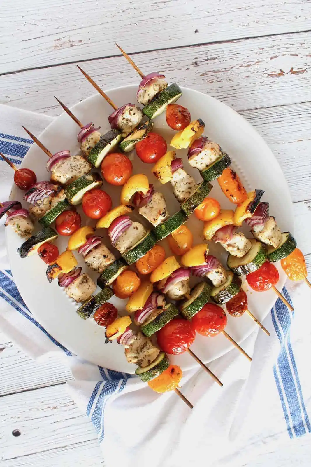 Lemon herb chicken kabobs on a white plate.