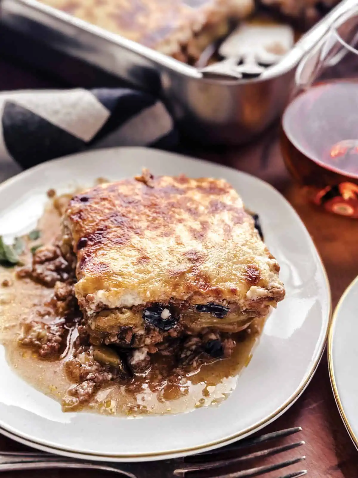 Moussaka serving on a beige plate with a fork.