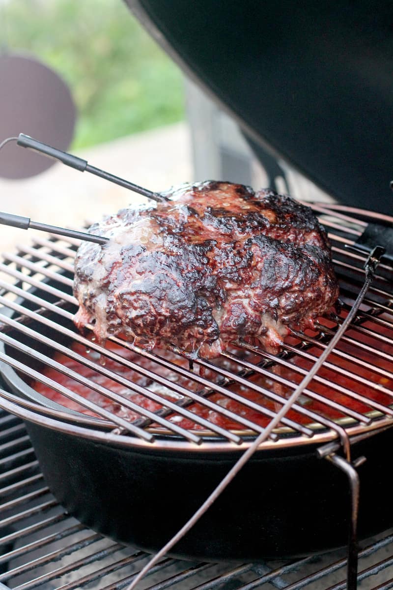 Ground beef chunk on a grilling grate oven a Dutch oven.