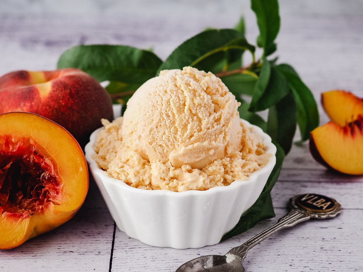 Peach ice cream in a white bowl.