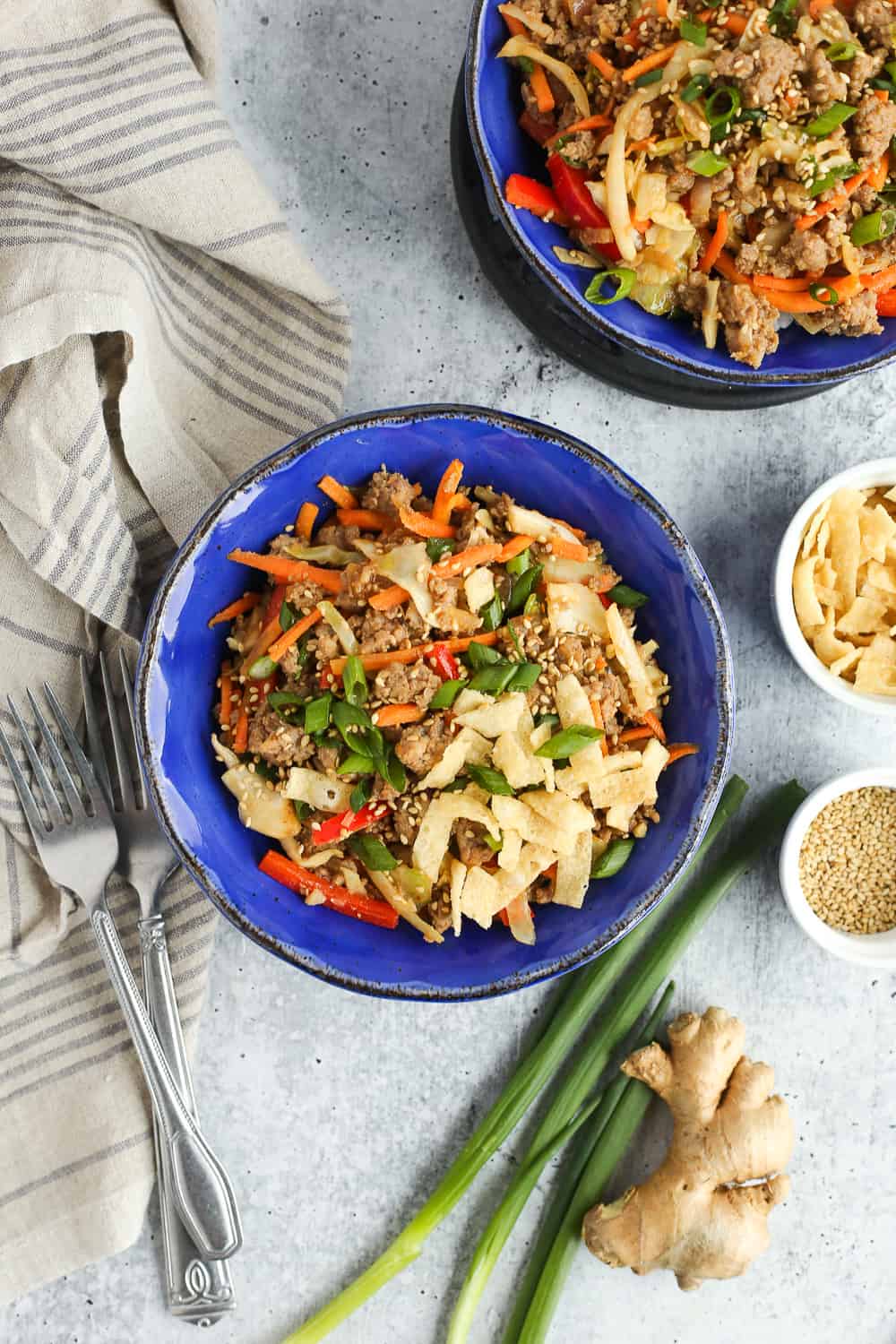 Blue bowl full of egg pork roll in a bowl with ingredients and forks surrounding it.