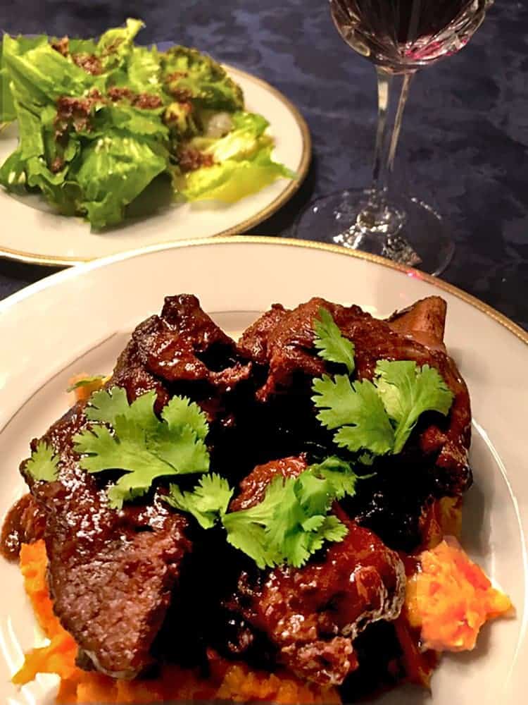 Short ribs served over pureed root vegetables on a plate.