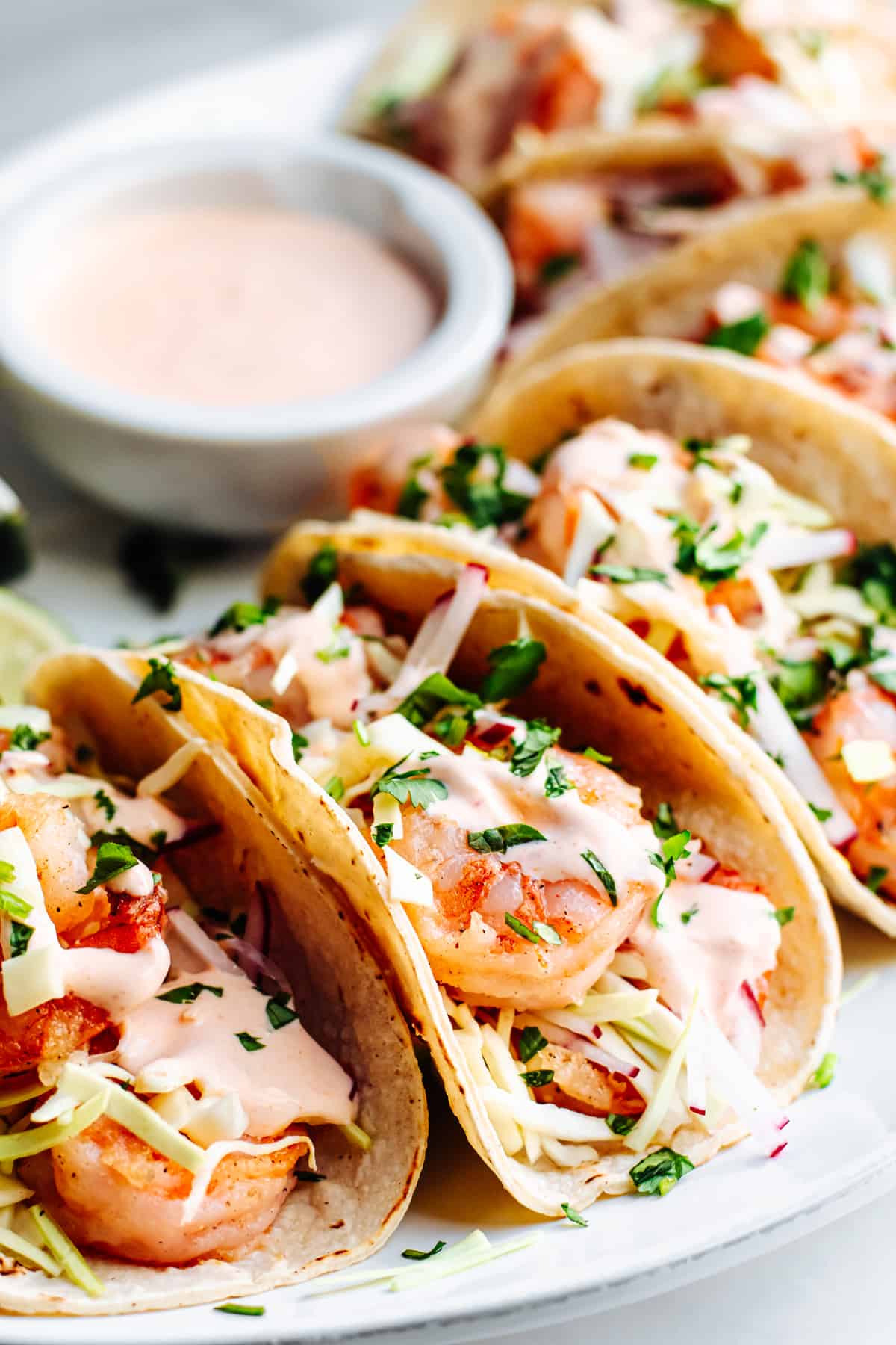 Shrimp tacos on a plate with sauce.