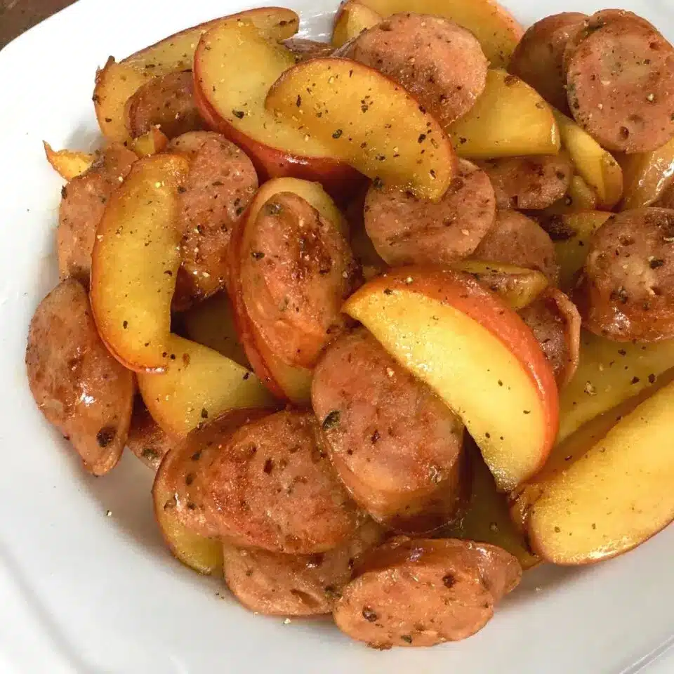 Skillet chicken sausage with apples on a white plate.