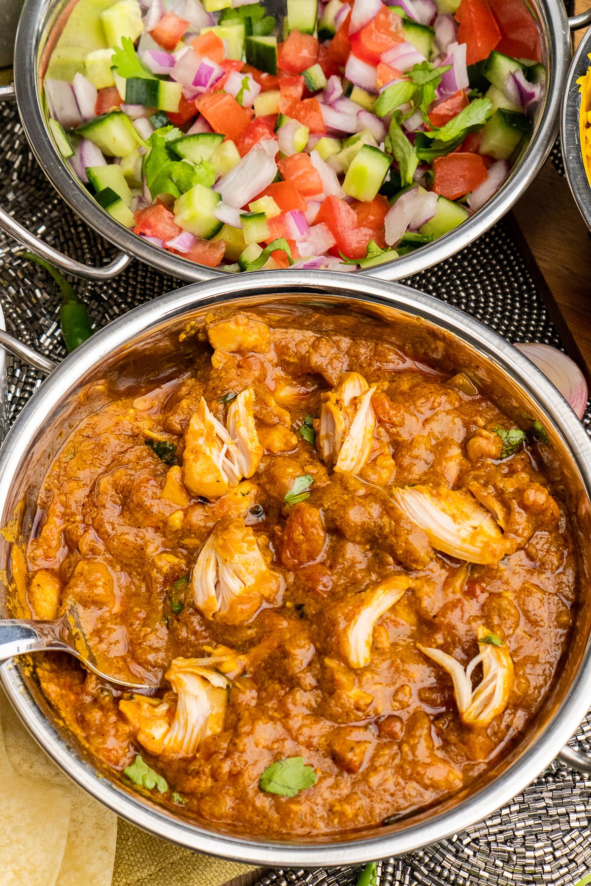 Pot full of chicken curry with serving spoon.