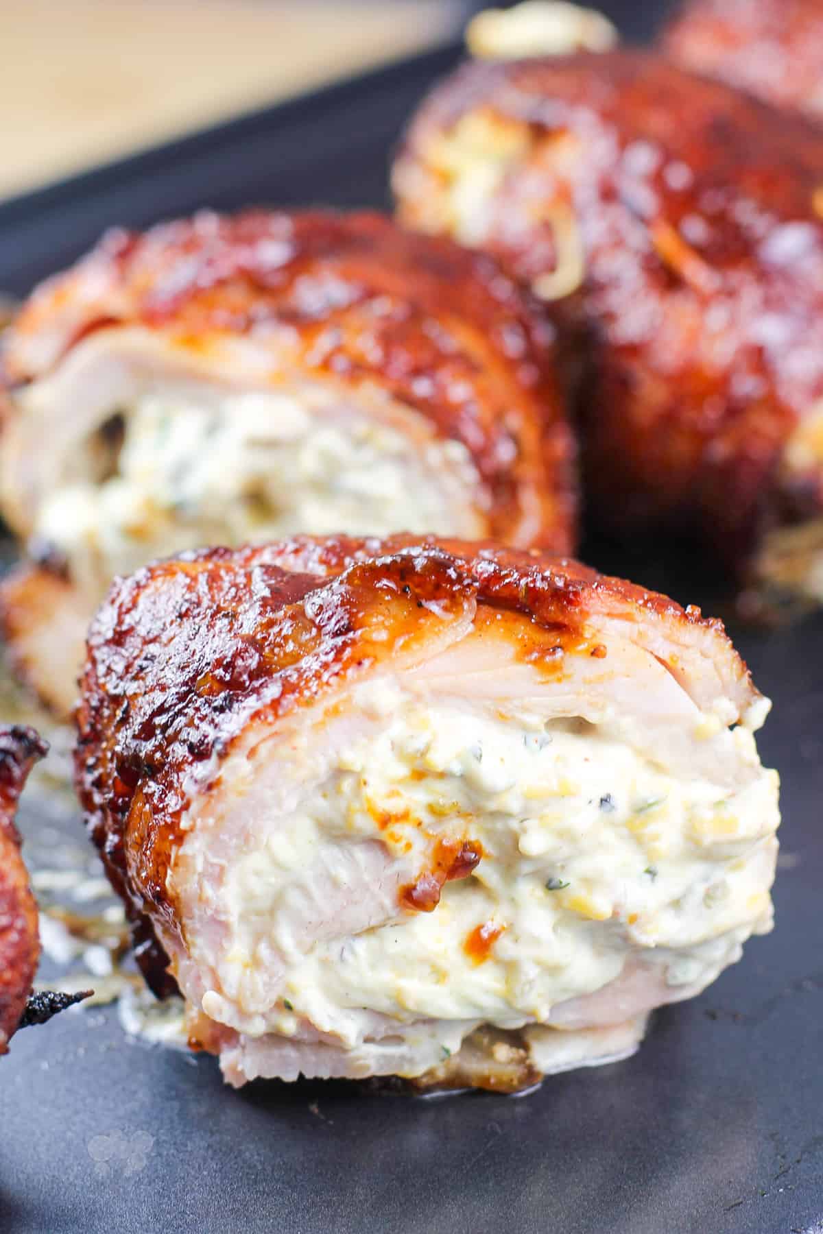 Close up of jalapeno stuffed chicken bombs on a black surface.