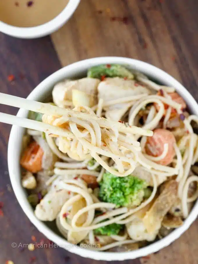 Thai peanut chicken noodle stir fry in a white bowl.