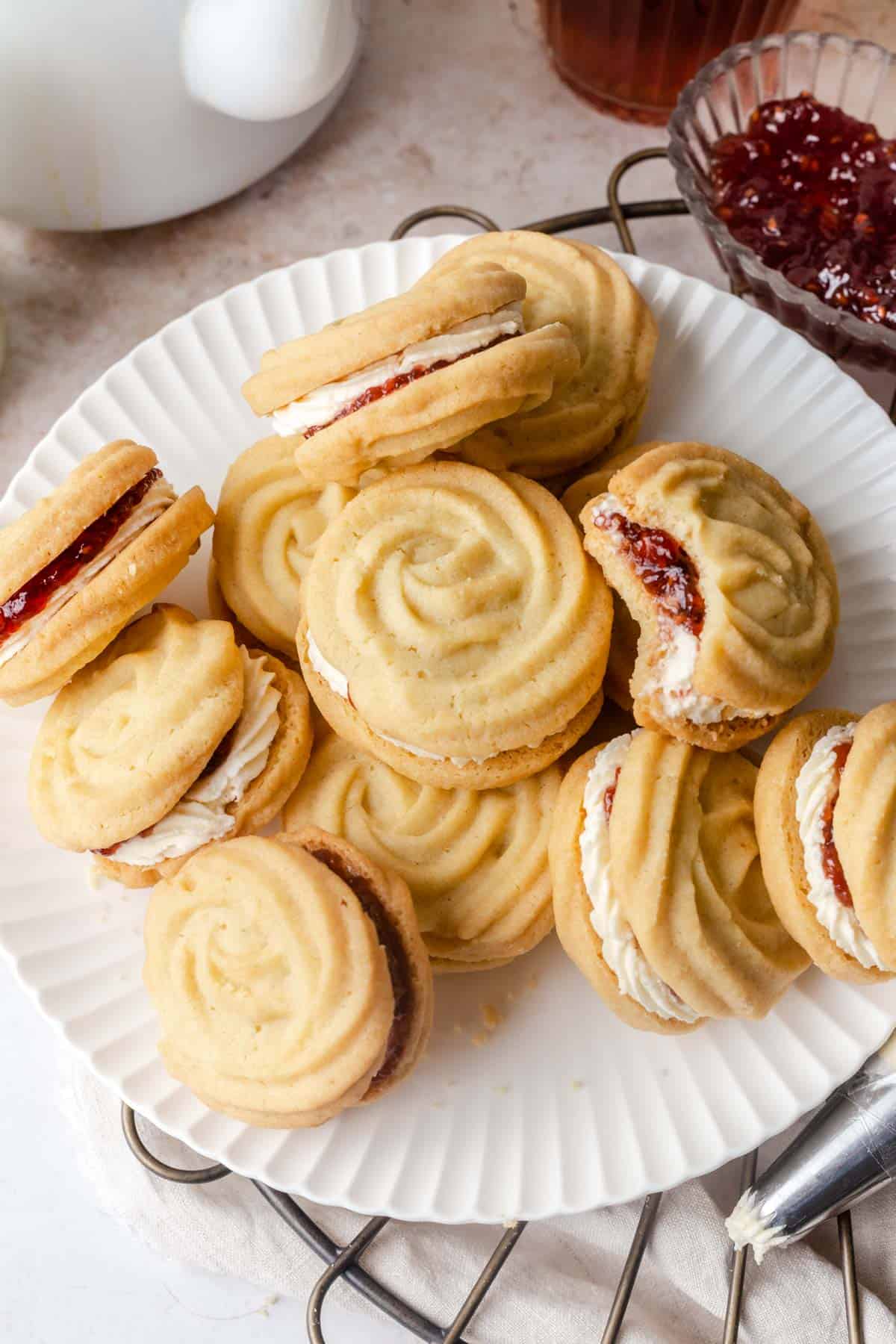 Viennese whirls on a white plate with jam on the side.