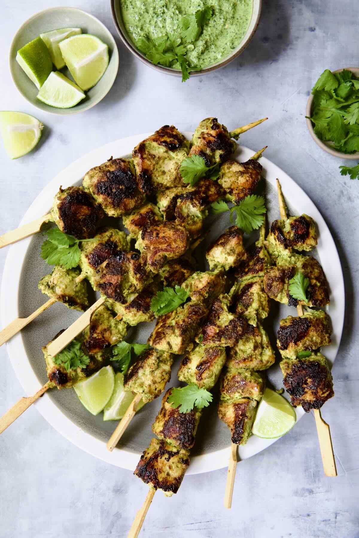 Yogurt marinated grilled chicken skewers on a white plate.