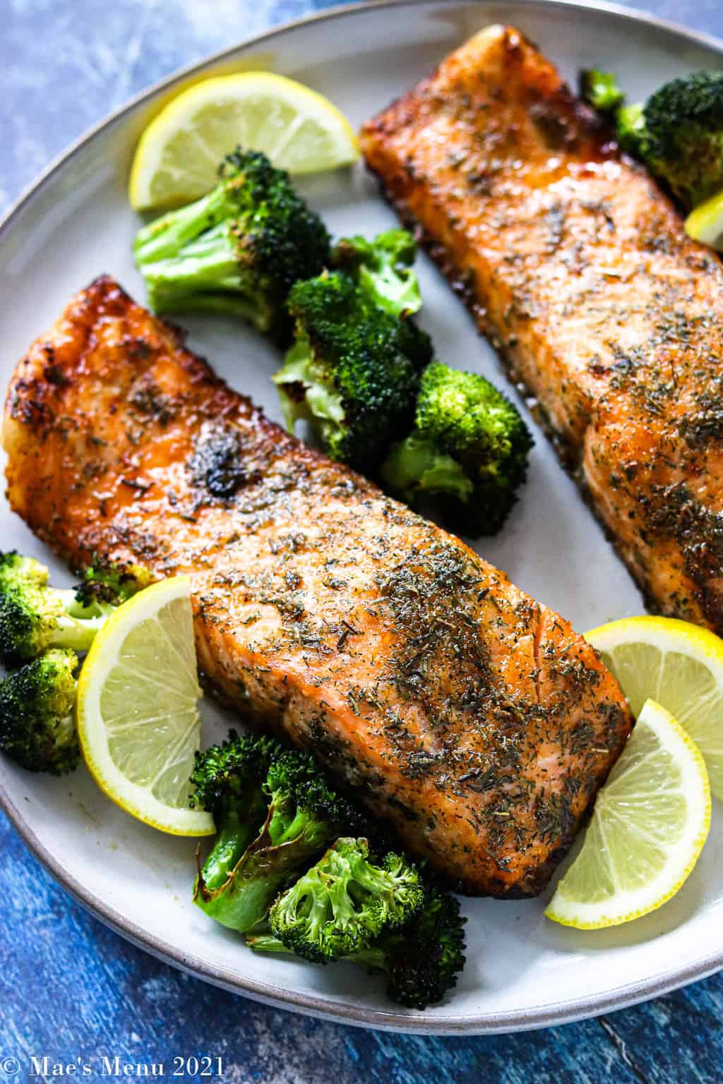 Air fryer salmon with broccoli and lemon wedges on a plate.