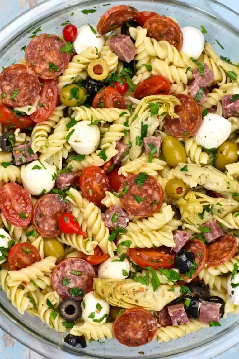 Antipasto pasta salad with mozzarella bowl, meat, tomato, and artichoke.