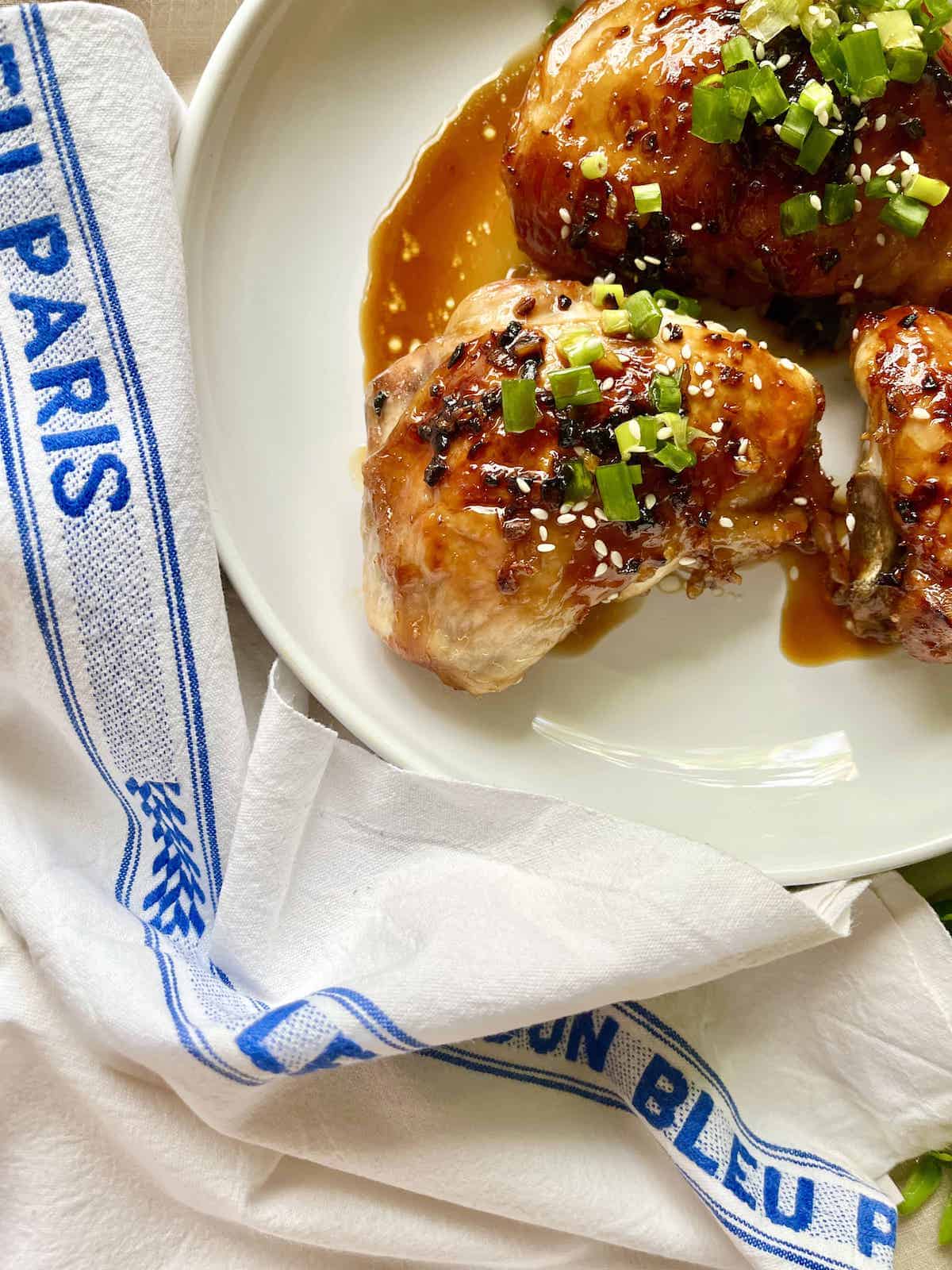 Baked teriyaki chicken thighs on white plate.