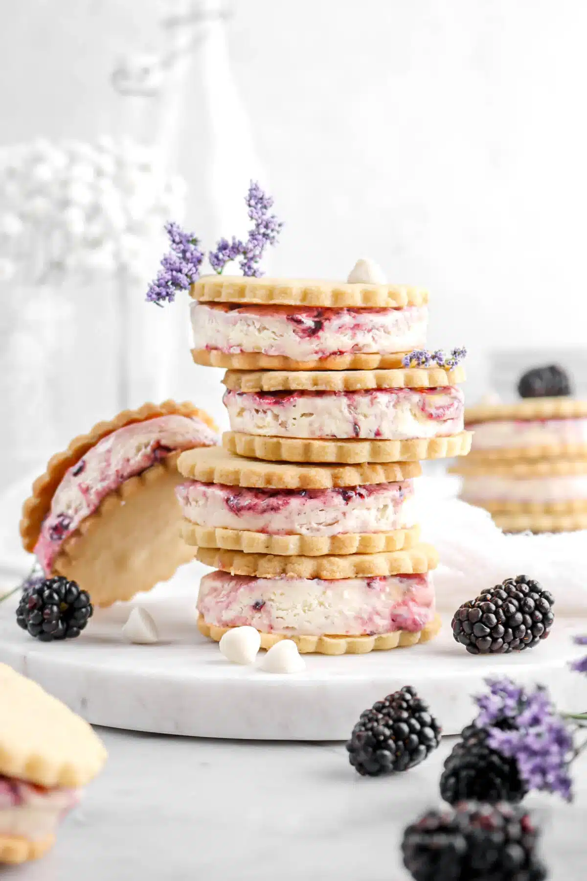 Stack of lavender blackberry ice cream sandwiches on a marble slab with blackberries in the background.