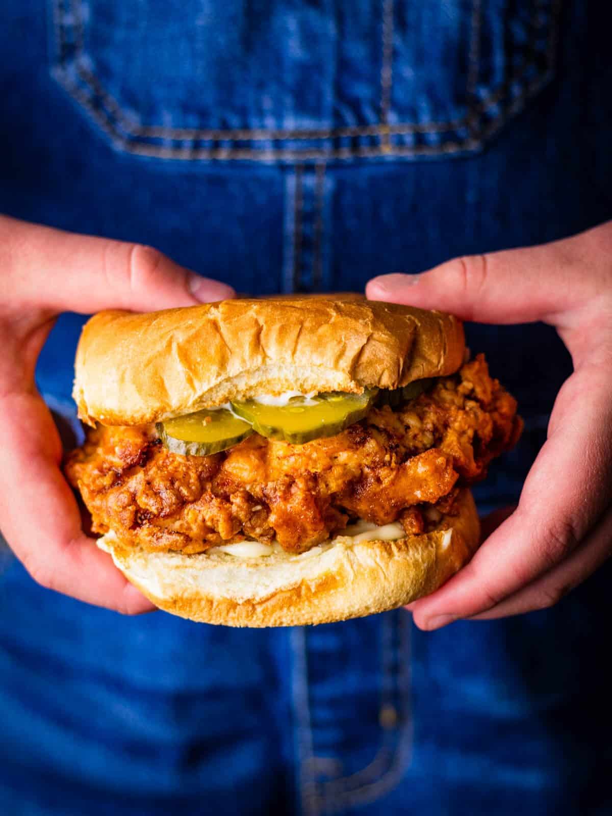 Hands holding a chicken salad with pickles.