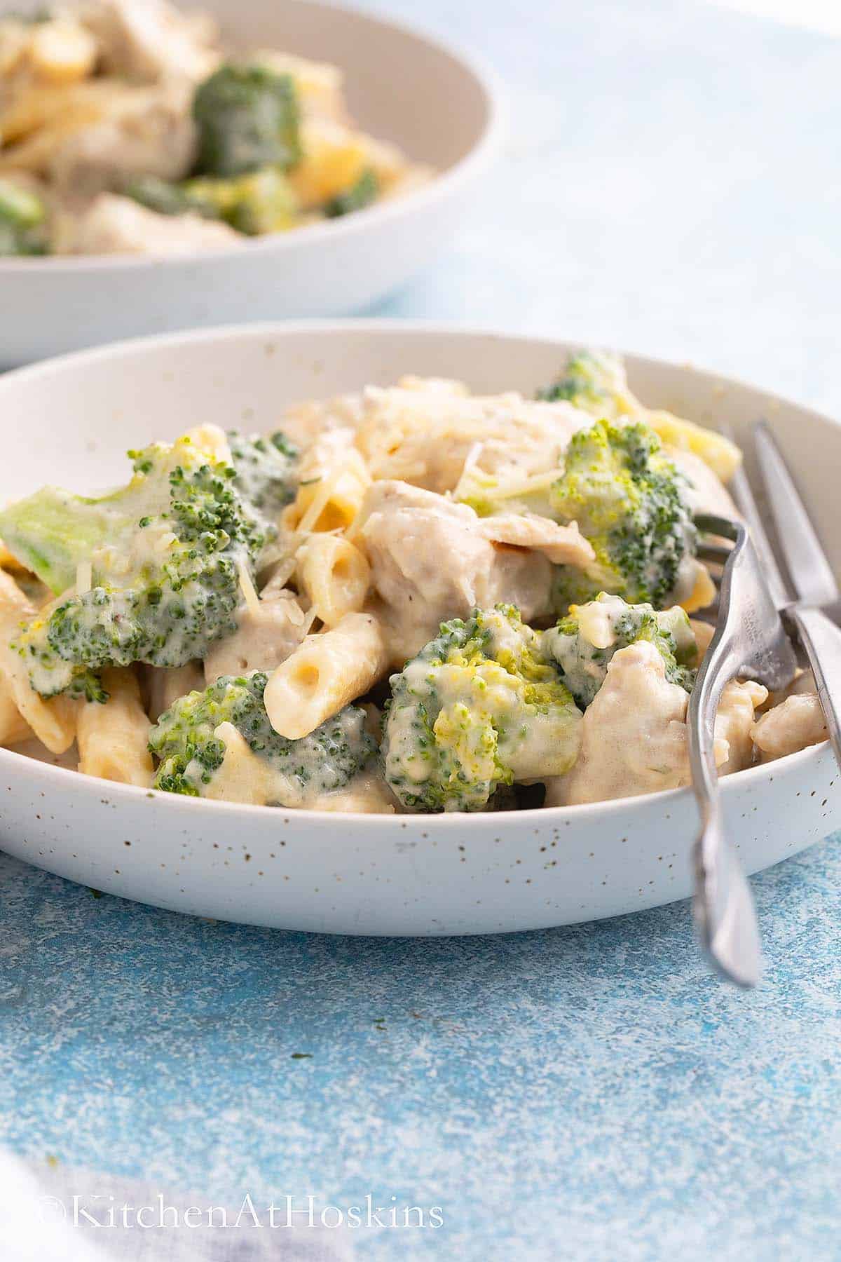 Chicken broccoli alfredo in a white dish with silverware.