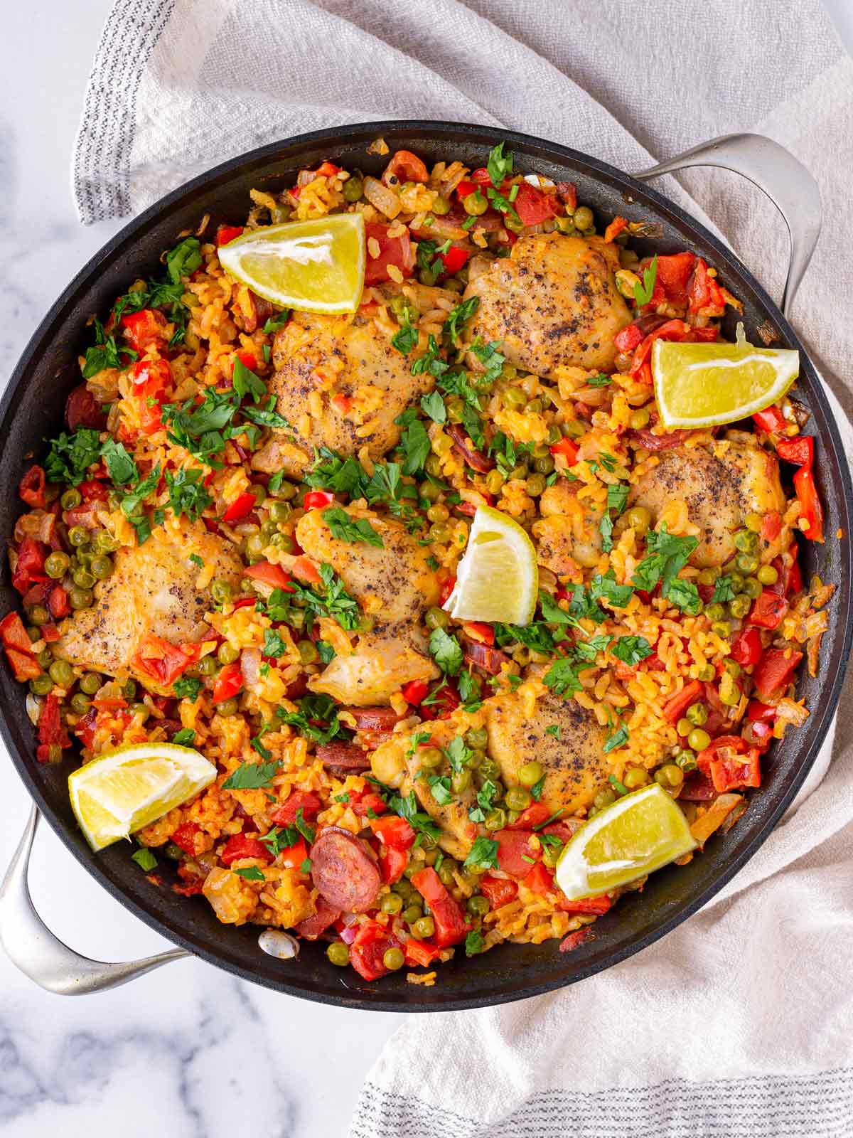 Colorful Spanish chicken and chorizo paella recipe in a black skillet.