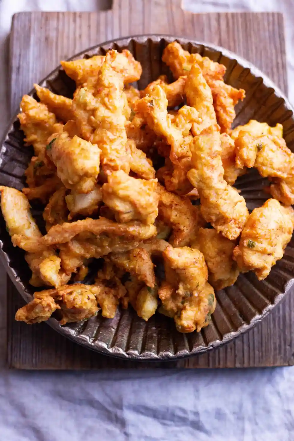 Fried chicken pakoras on a dark plate.