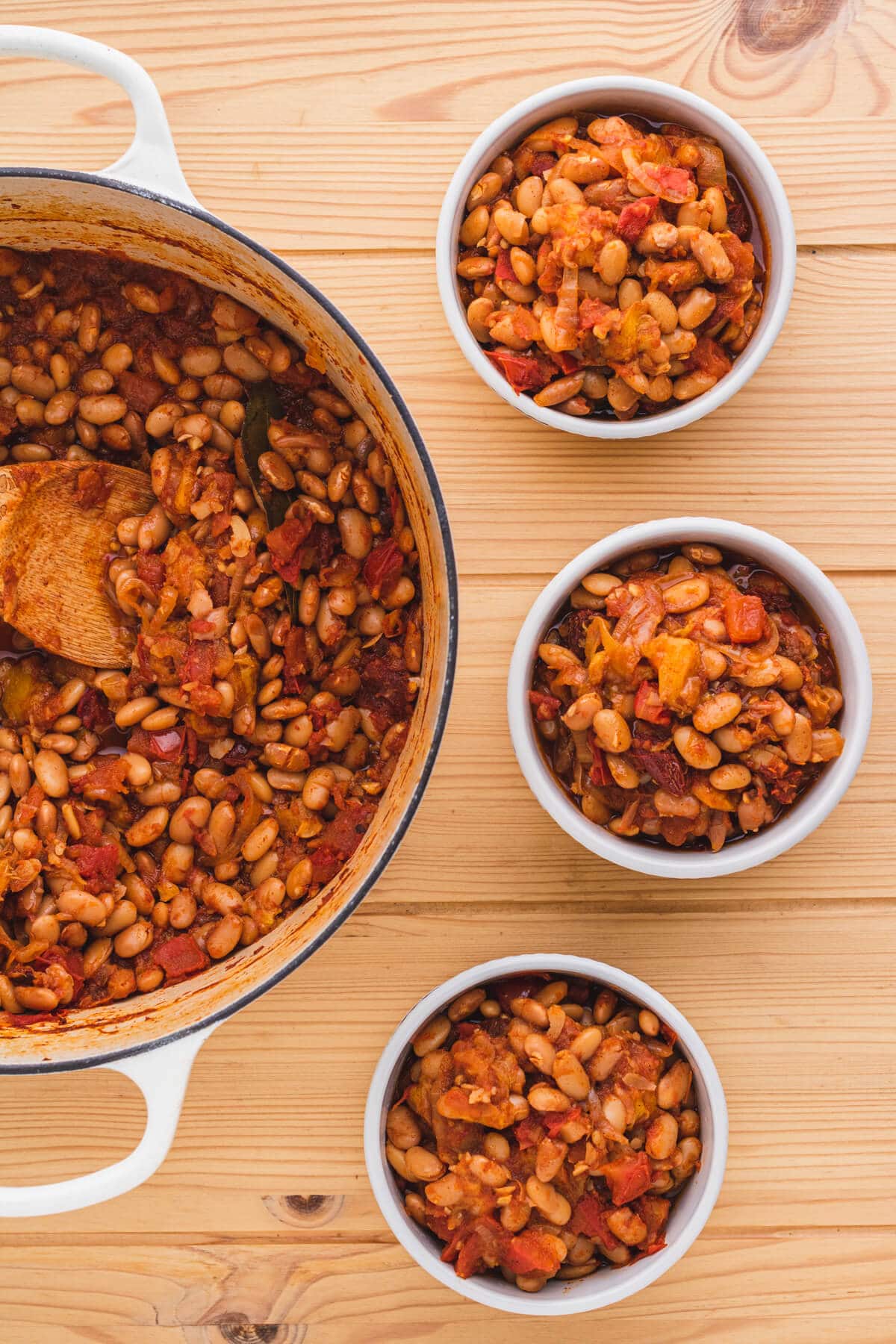 Chipotle pinto beans with peaches in a Dutch oven with servings in small bowls.