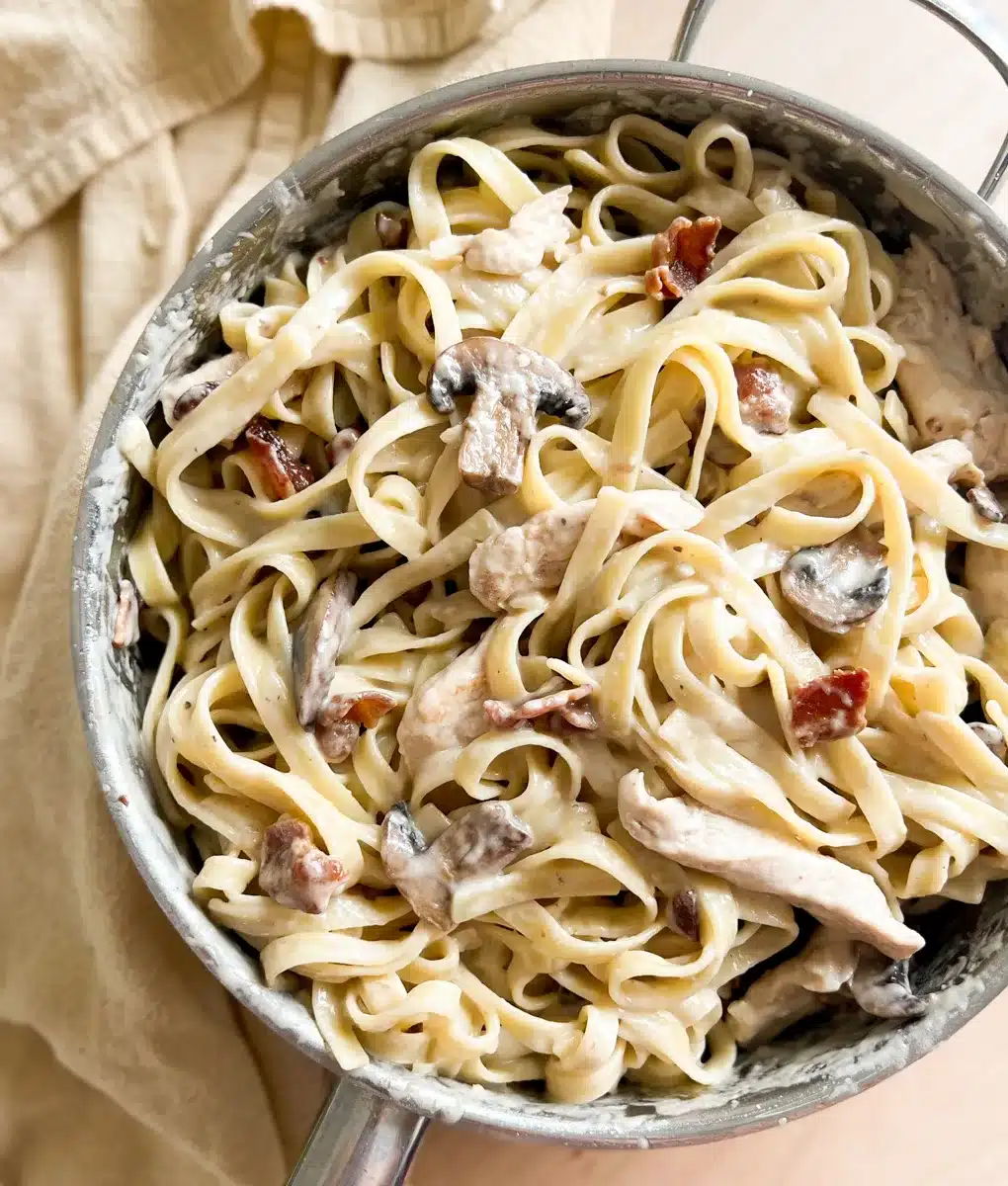 Creamy bacon, chicken, and pasta meal in a skillet.