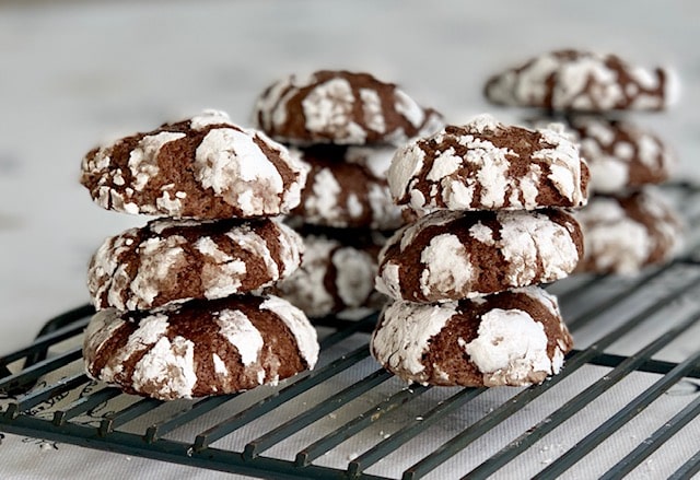 Stacks of dark chocolate crinkle cookies on a cooling rack.