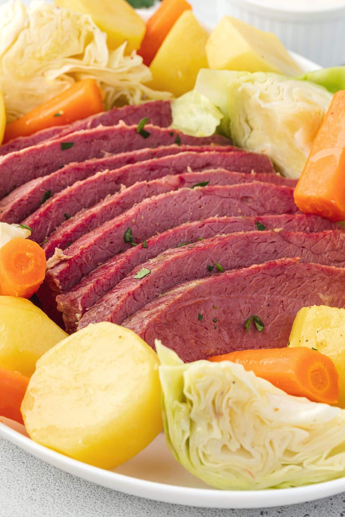 Corned beef surrounded by carrots, potatoes, and cabbage.
