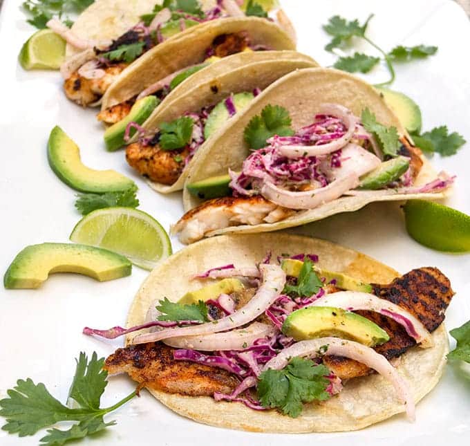 Blackened fish tacos with cilantro lime slaw on a white background.