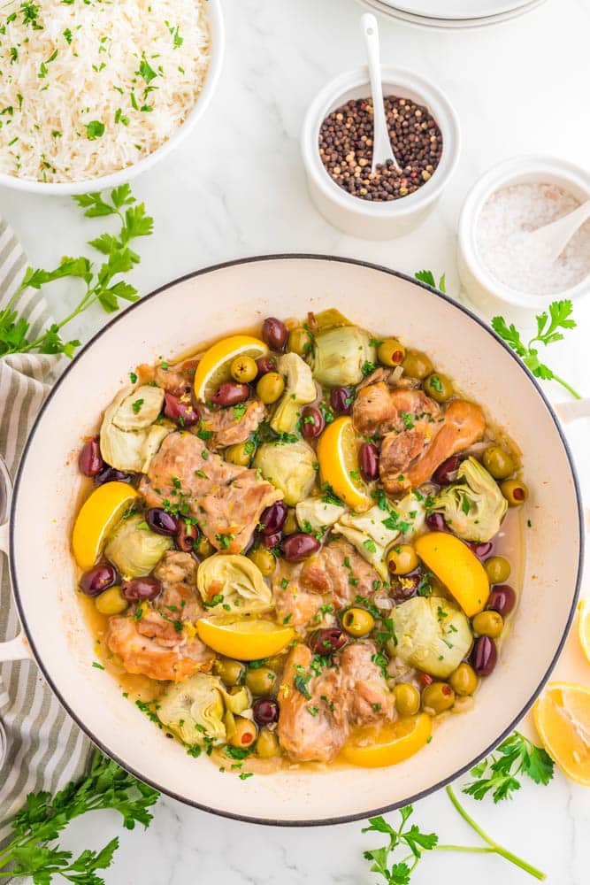 Greek chicken thighs with olives, garlic, shallots and artichokes in a Dutch oven.