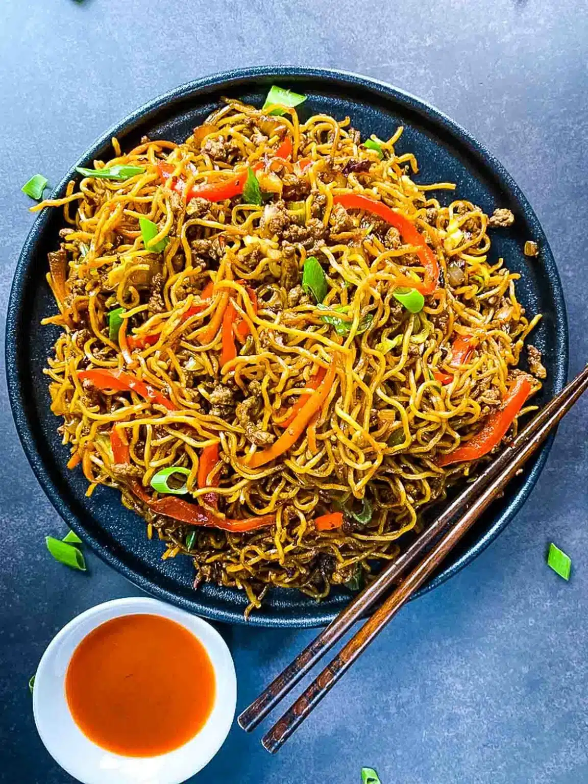 Ground beef stir fry noodles on a serving platter with chopsticks.