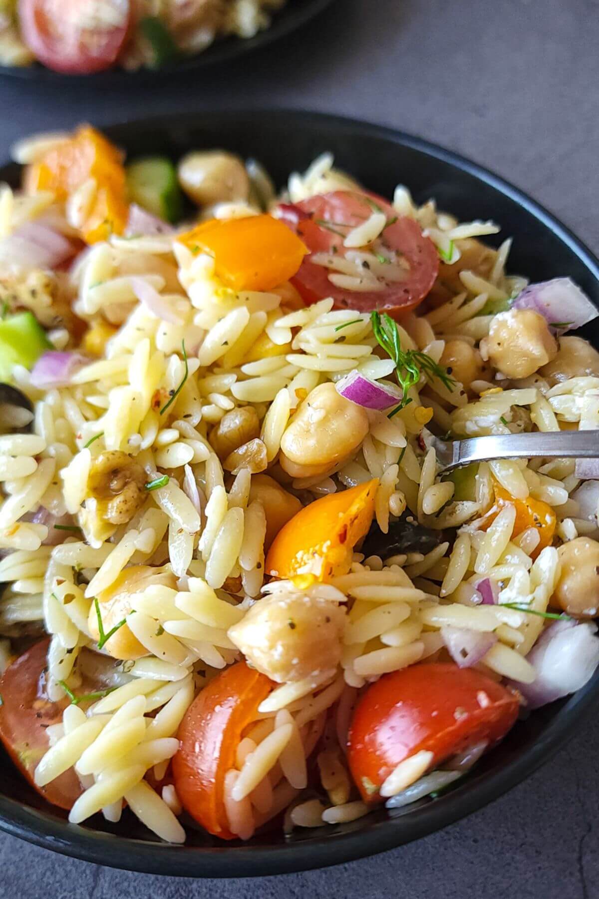Orzo salad with feta in a black bowl.