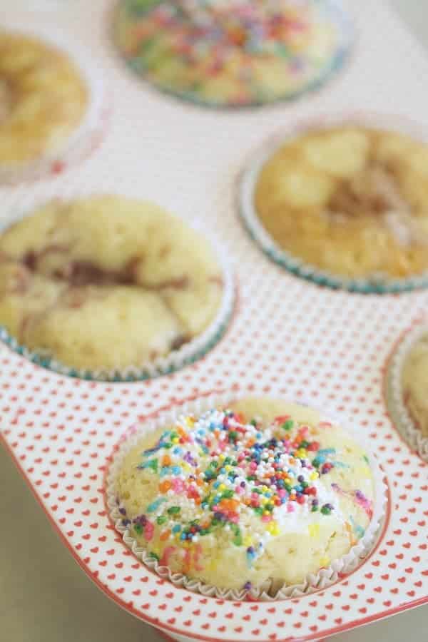 Pancake muffins with sprinkles in a muffin tin.