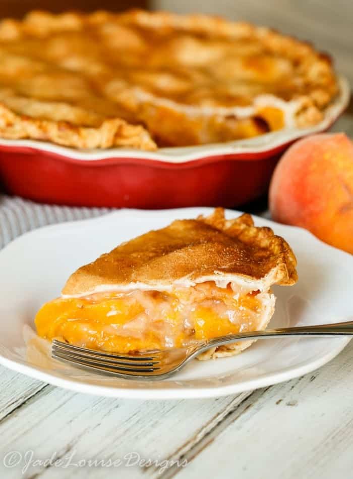 Slice of peach pie with cinnamon crust on a white plate.