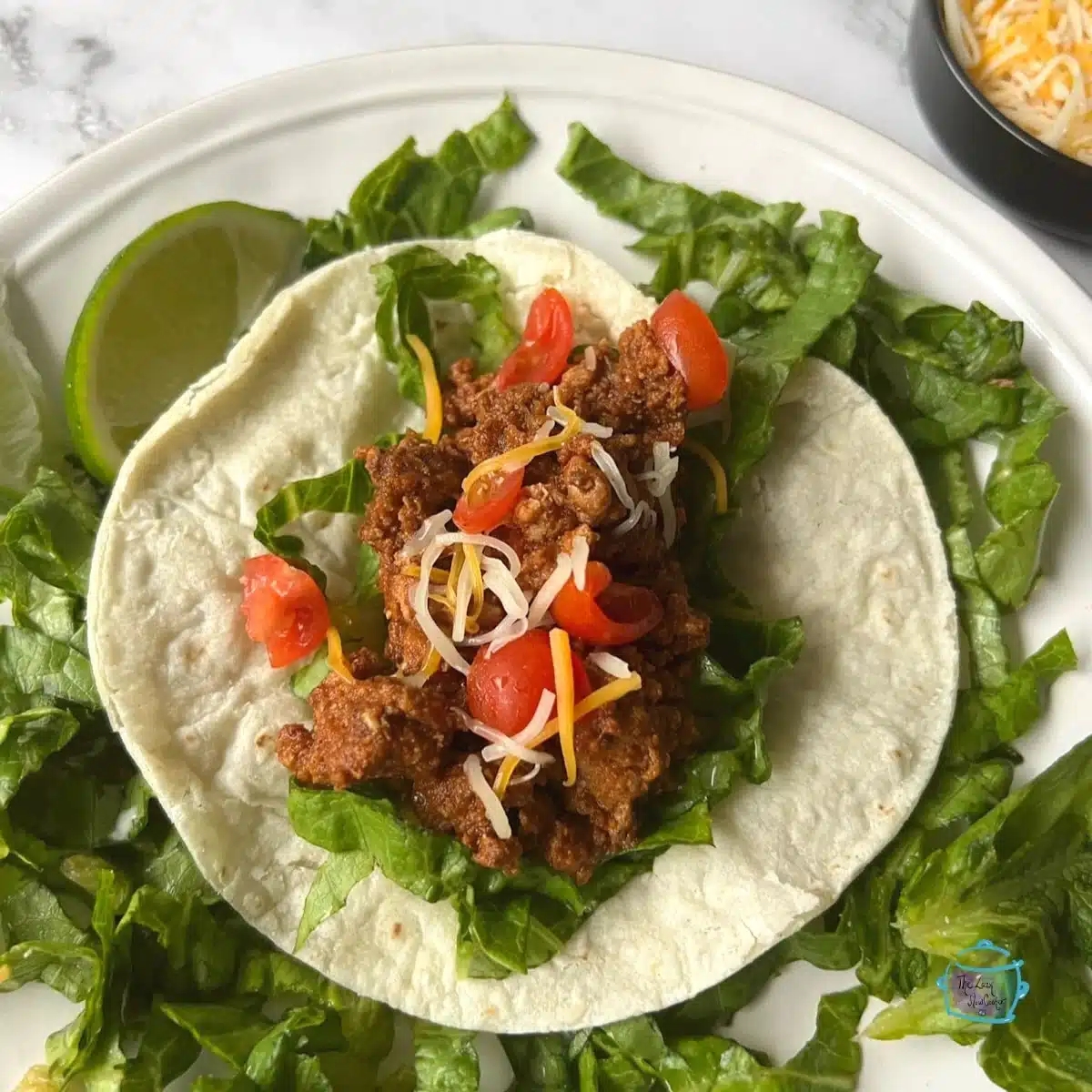 Ground turkey taco on a white plate with lime wedge.