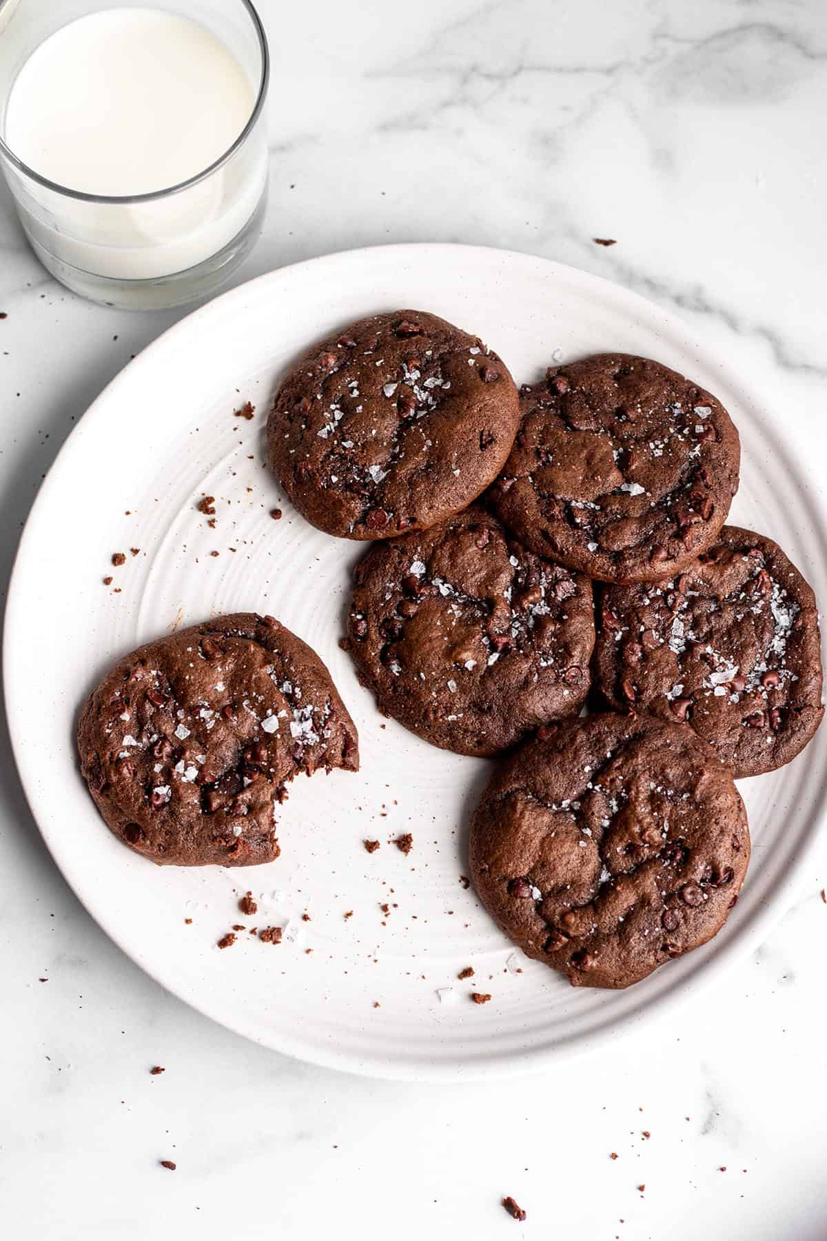 Chocolate cookies with flaky salt on a white plate.