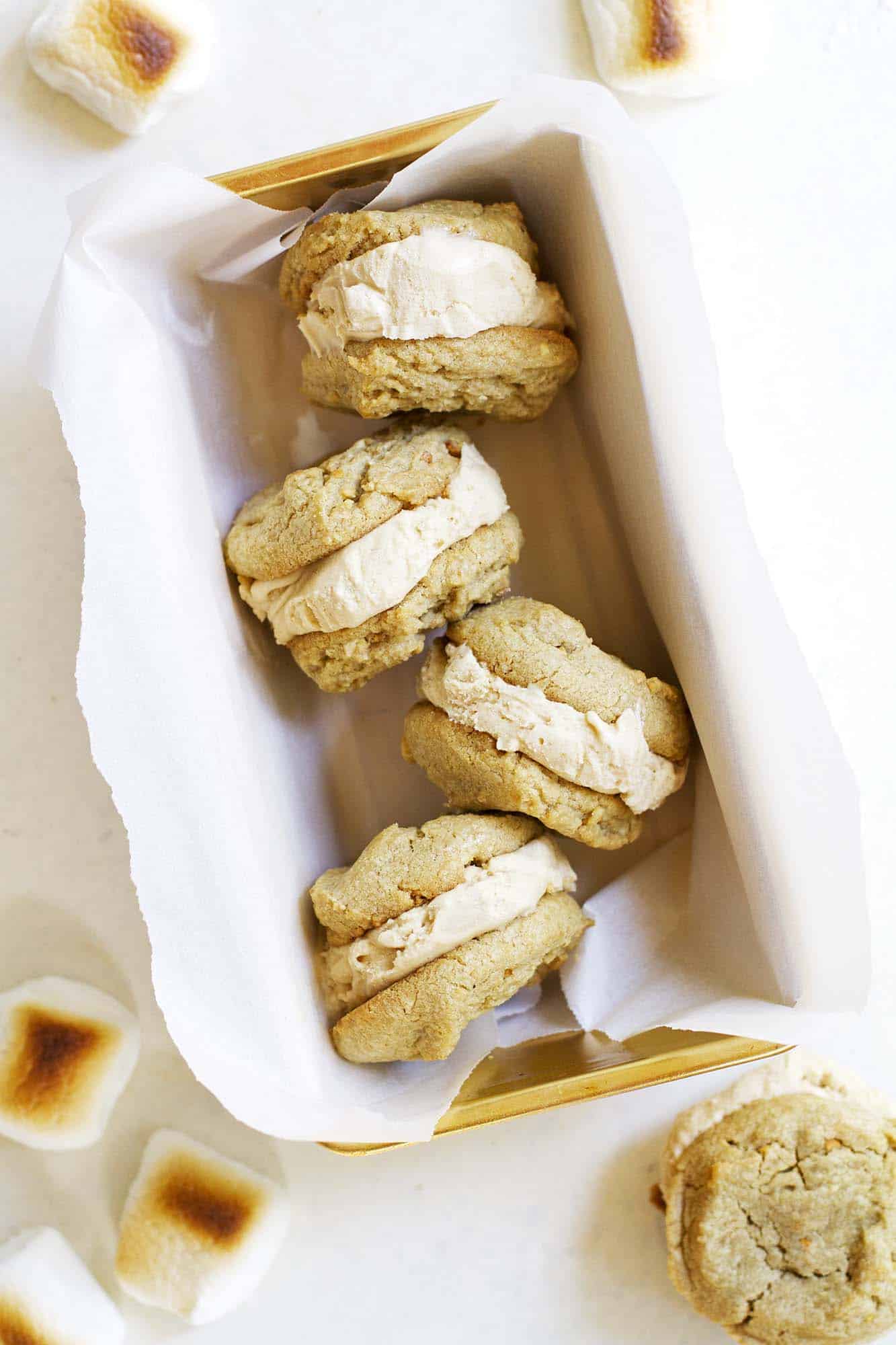 Toasted marshmallow peanut butter ice cream sandwiches in a parchment lined pan.