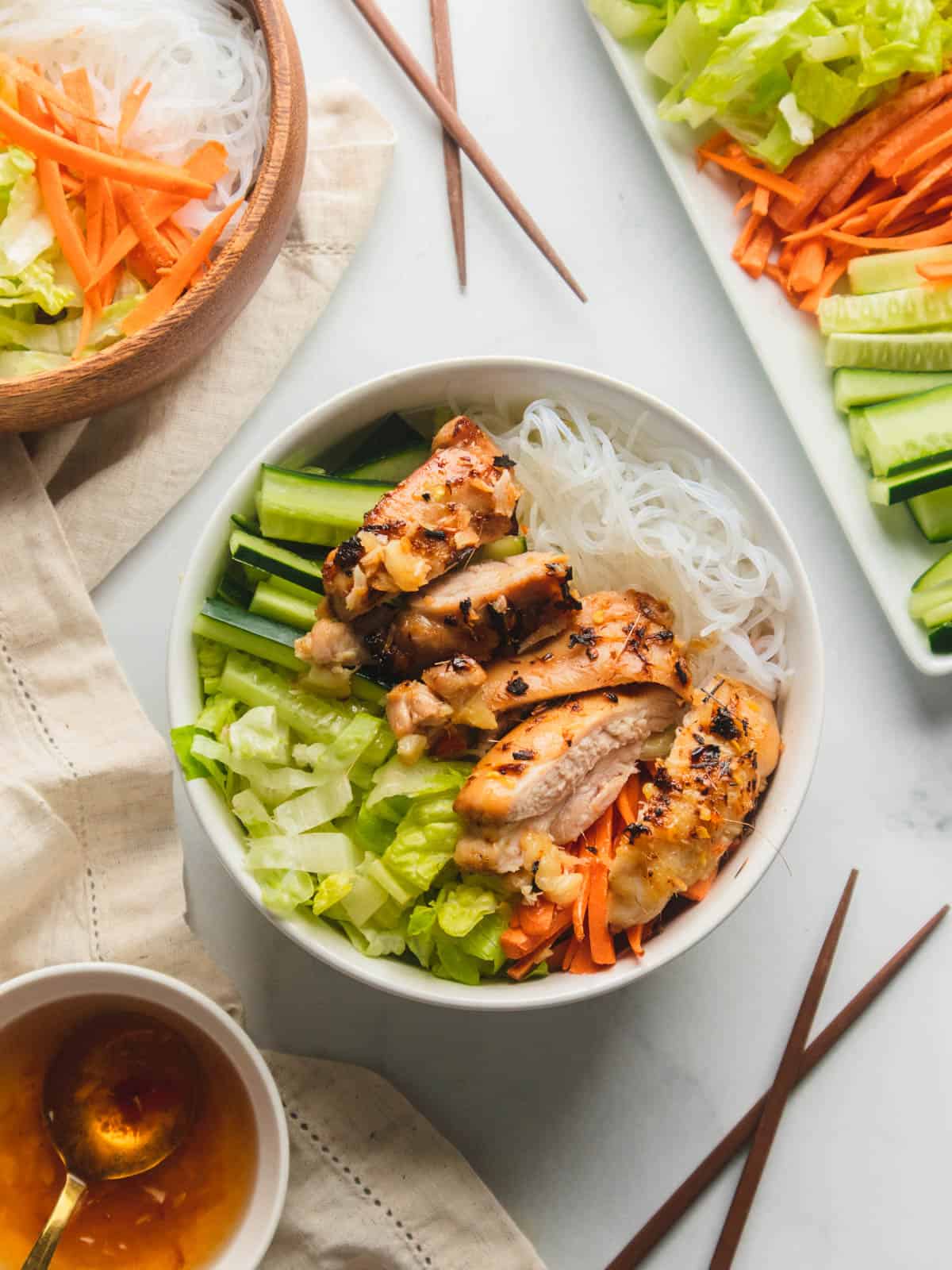 Vermicelli rice noodle salad in white bowls with chopsticks in the background.