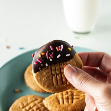 Hand holding a 2 ingredient peanut butter cookie dipped in chocolate.