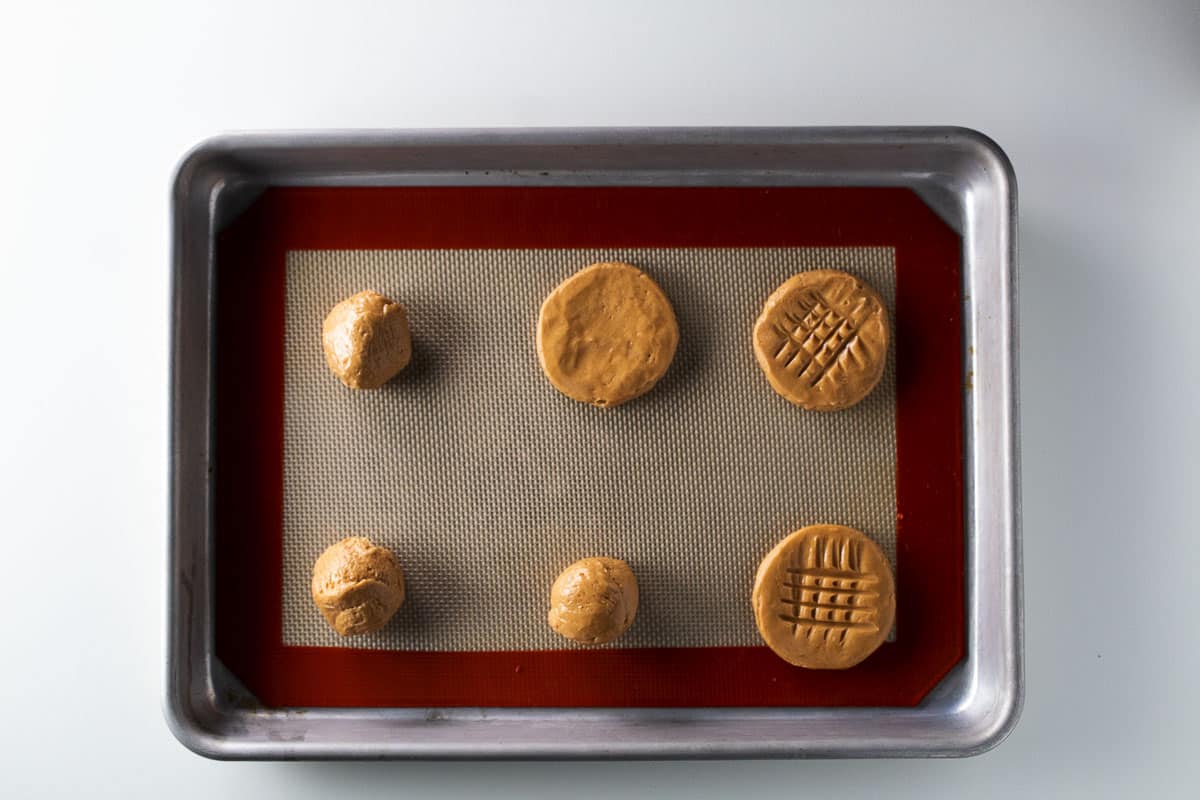 Raw peanut butter cookie dough on a silicone baking mat lined baking tray.