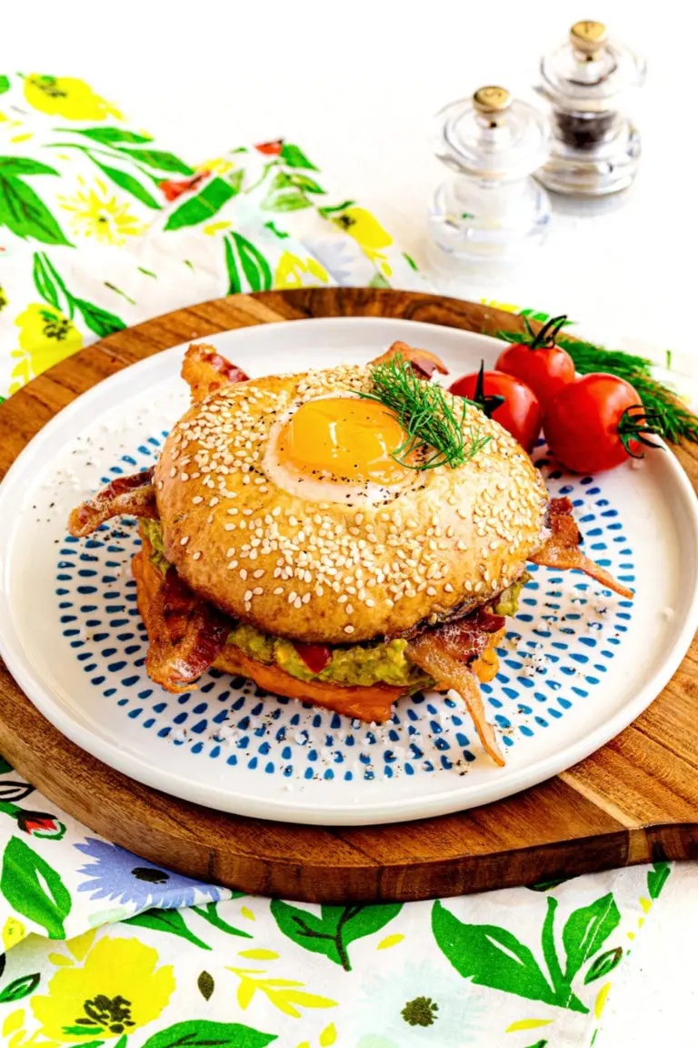 Egg in a hole bagel breakfast sandwich on a decorative blue and white plate.