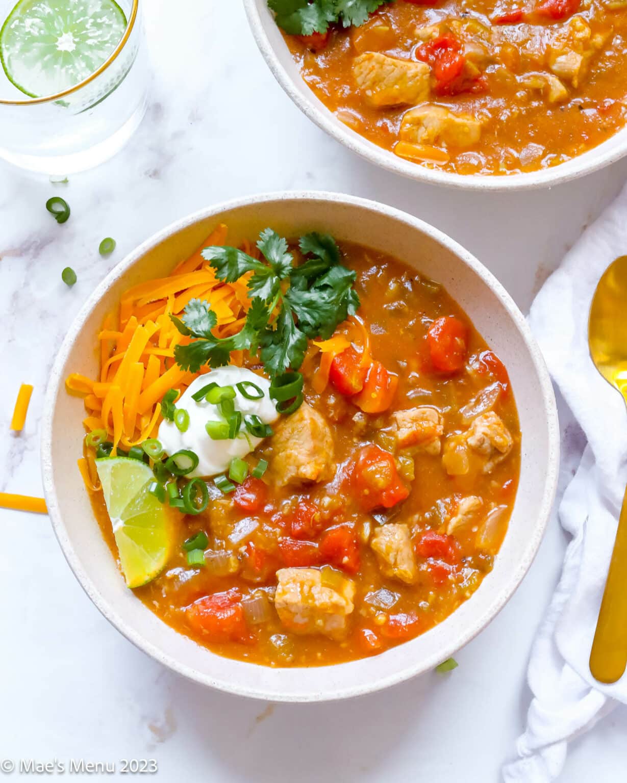 Colorado style pork green chili with lime wedge in a white bowl.