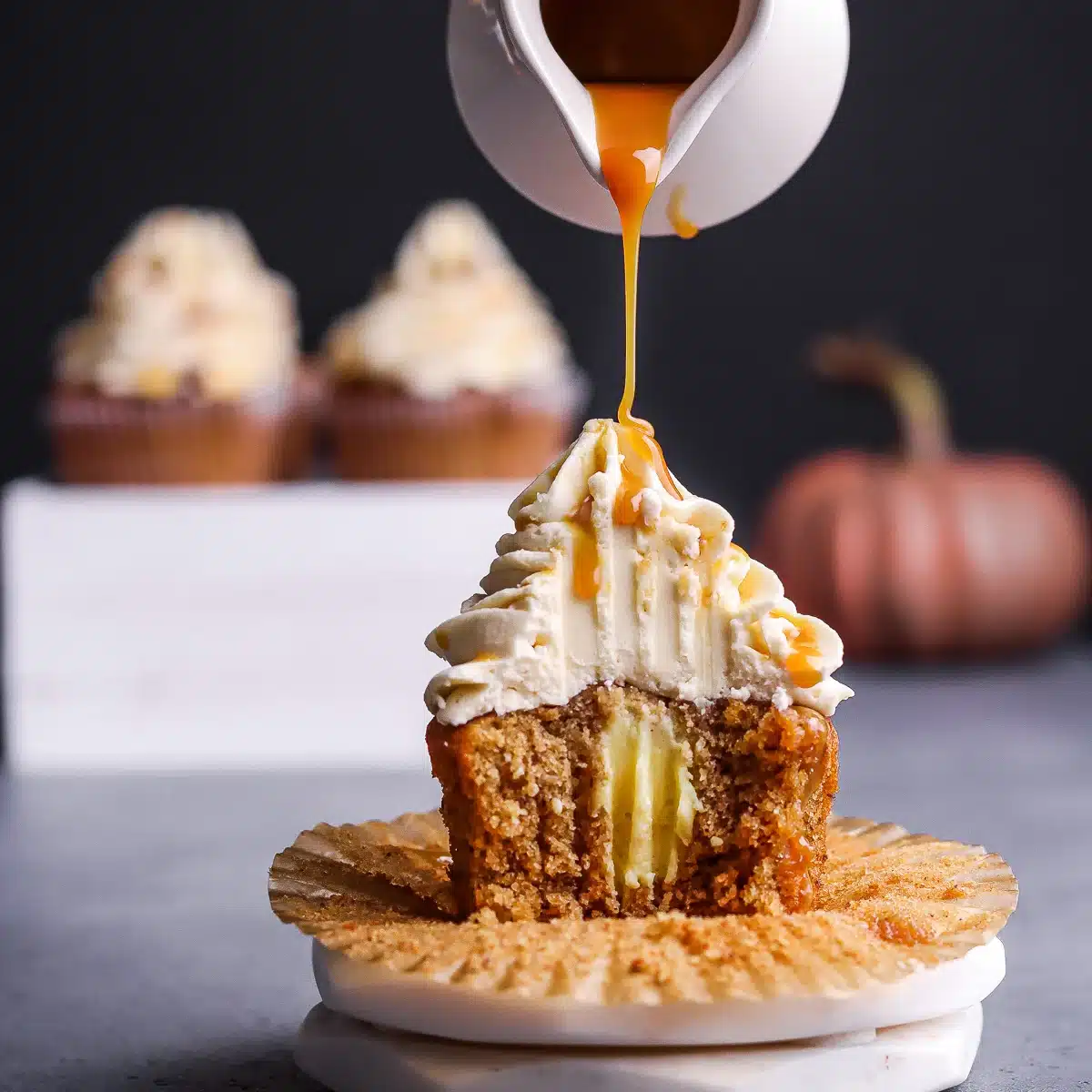 Pouring caramel sauce on top of a hazelnut cupcake.