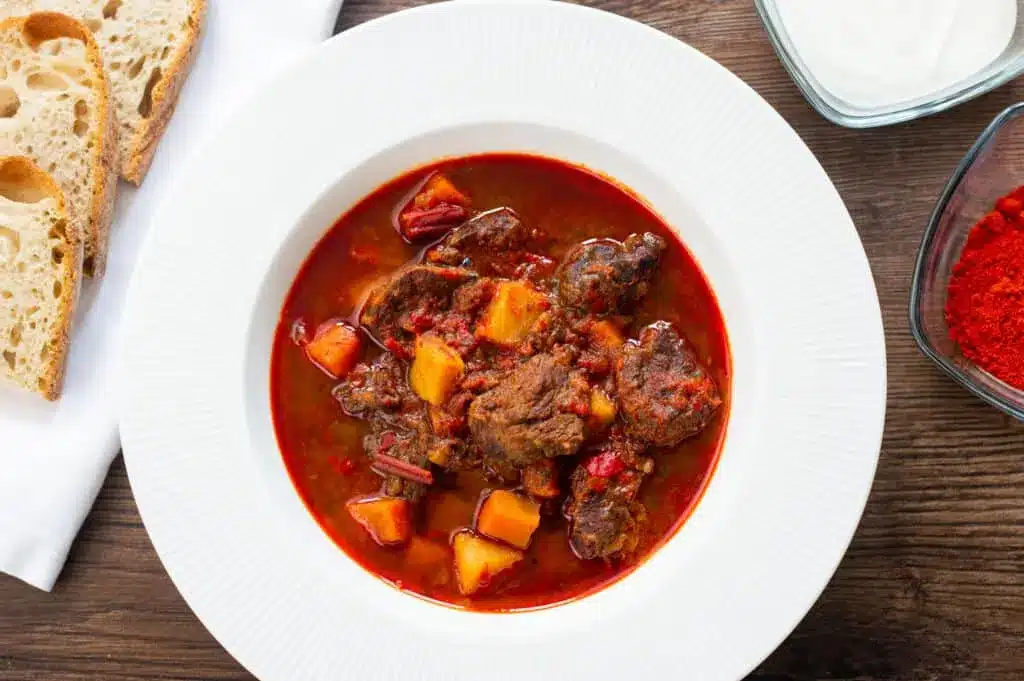 Red Hungarian goulash in a white bowl.