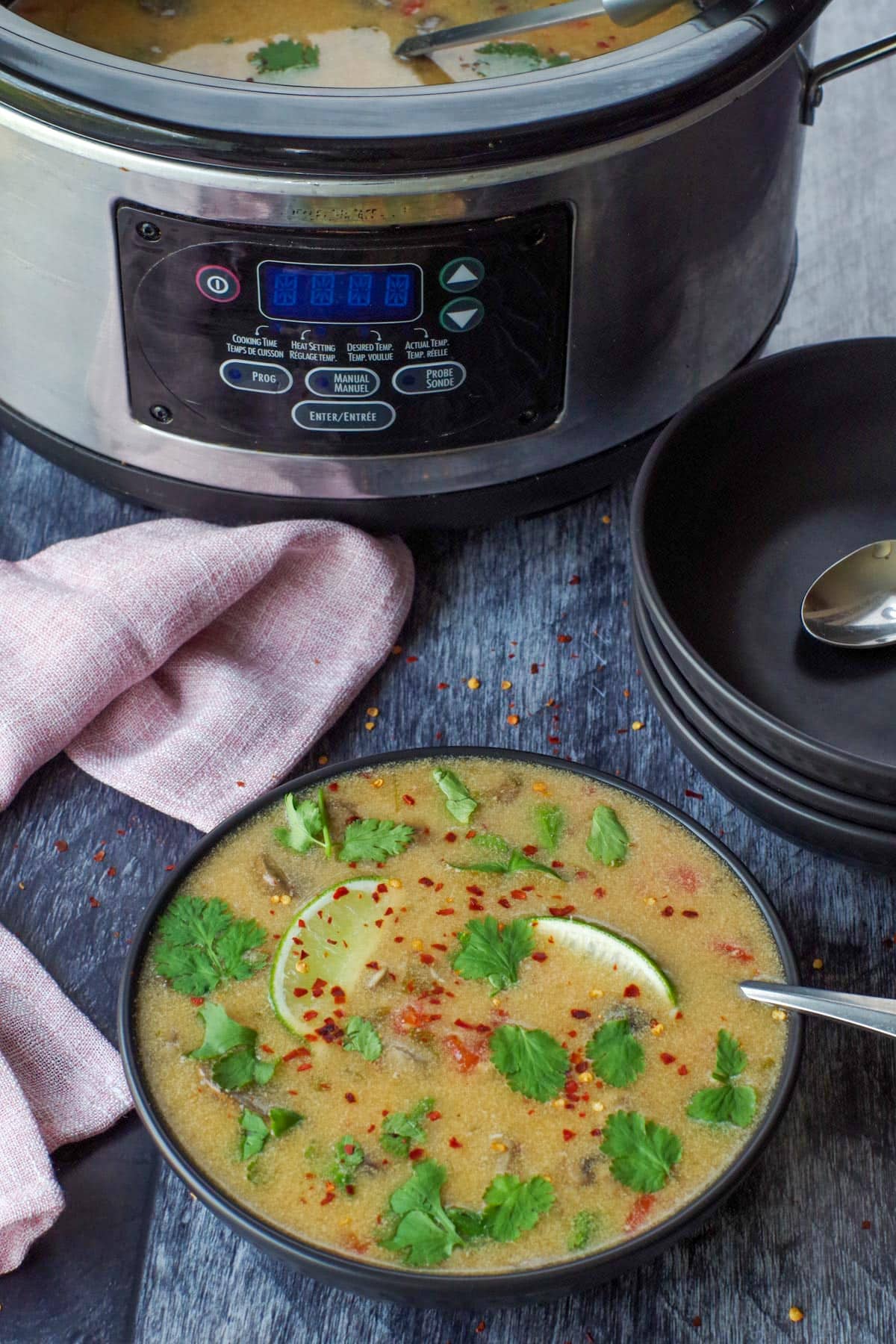 Slow cooker Thai chicken soup in a dark bowl.